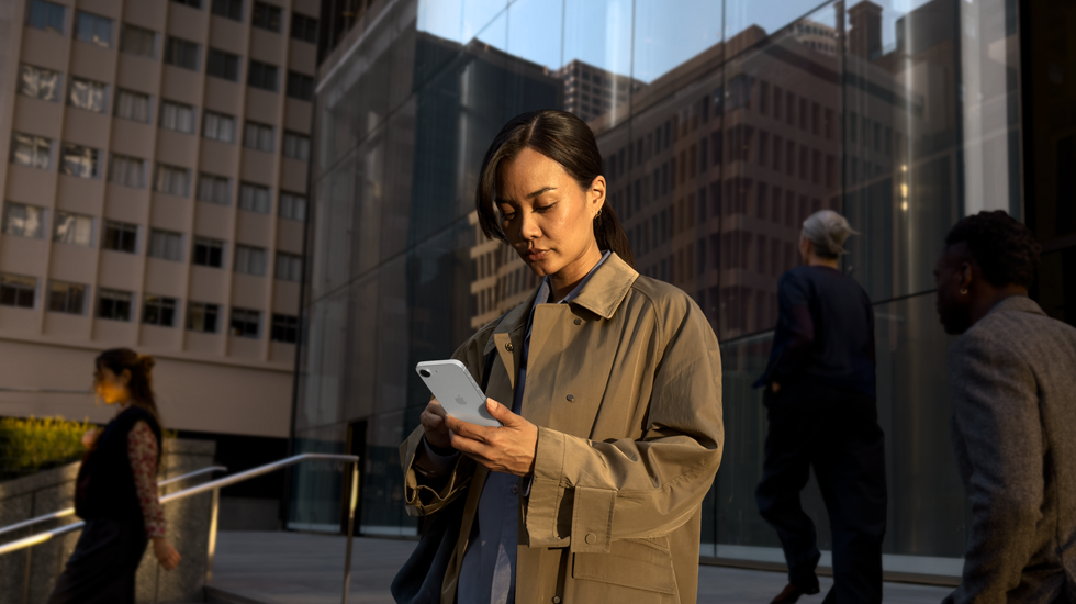 Une personne utilisant un iPhone 17e blanc pour poursuivre son travail en extérieur