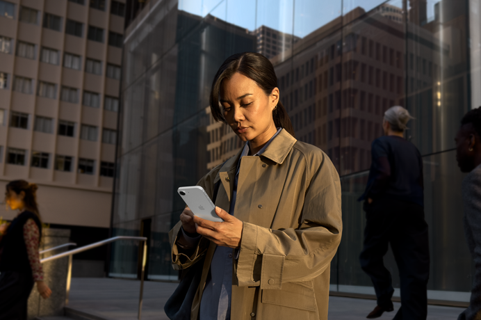 Une personne utilisant un iPhone 17e blanc pour poursuivre son travail en extérieur